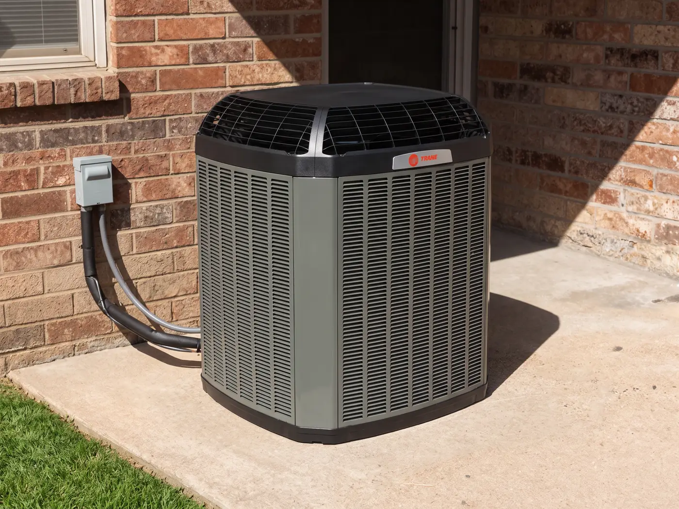 New Trane XV20i condenser on a concrete pad beside a red-brick house